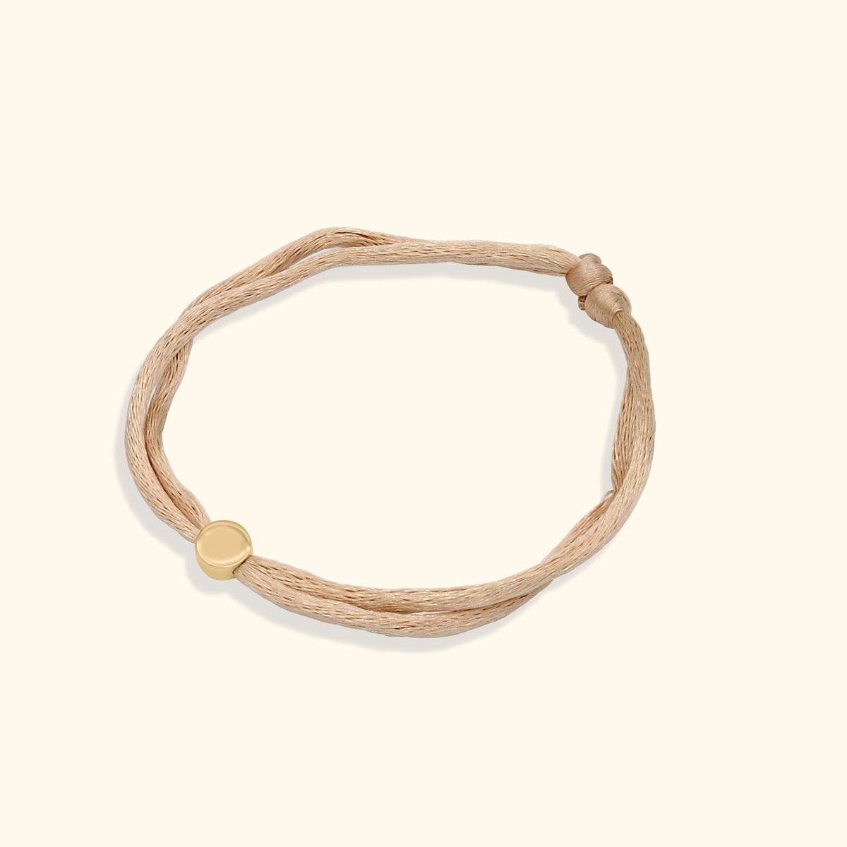 Persoonlijke armband met letterbedel aan een verstelbaar beige satijnen koord.