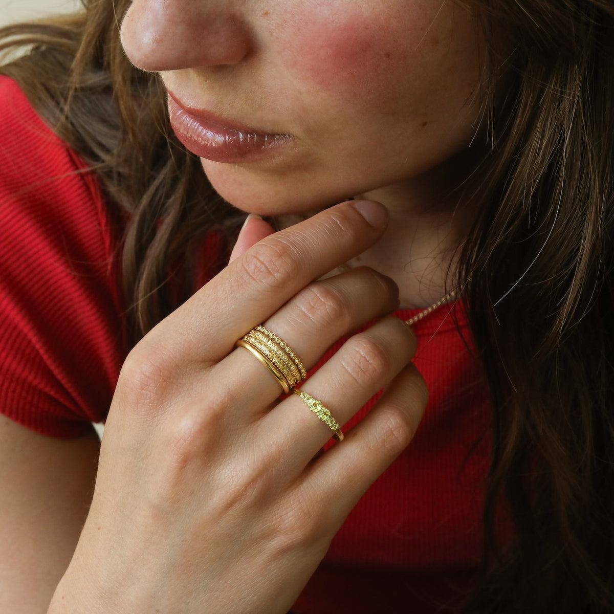 hand met gold plated stacking ringen met relief 

