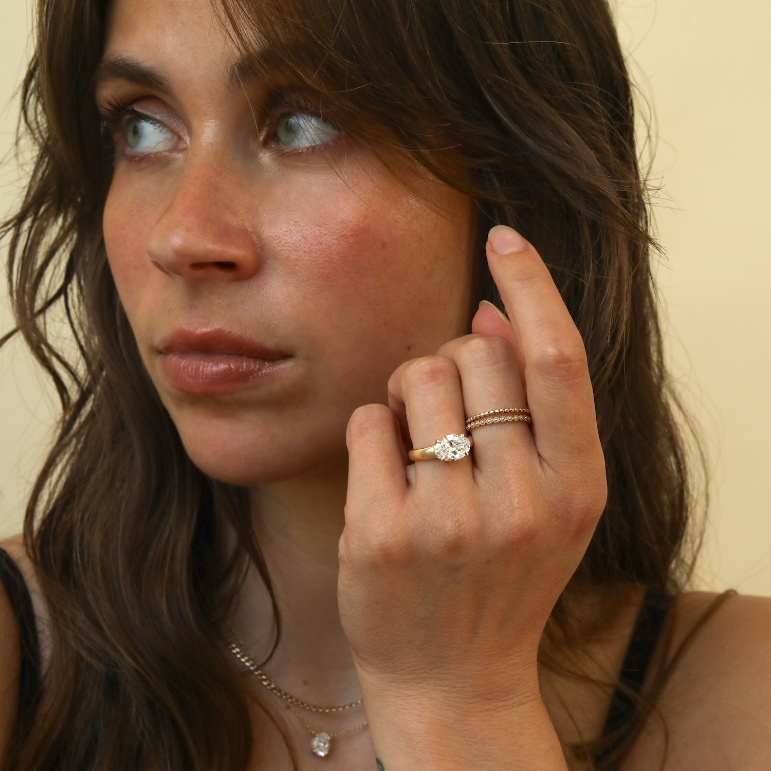Model draagt de Éloise 2 ct East to West Oval Diamond Ring in 14K goud met lab grown diamant en double hidden halo.