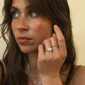 Model draagt de Éloise 2 ct East to West Oval Diamond Ring in 14K goud met lab grown diamant en double hidden halo.