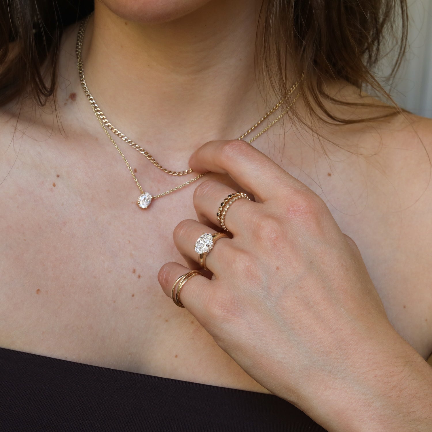 Close-up van de Éloise 2 ct East to West Oval Diamond Ring met bijpassende 14K gouden oval diamond ketting.