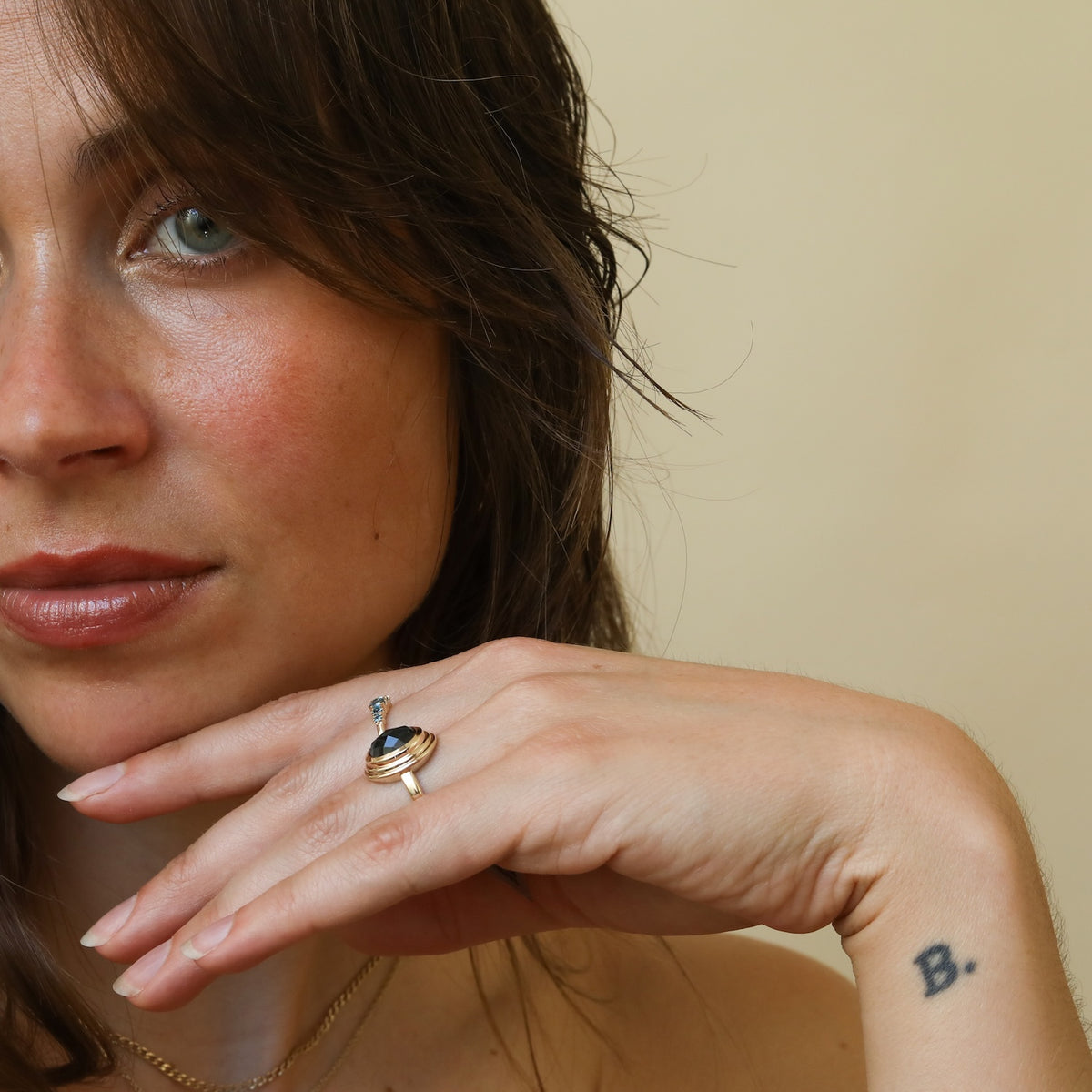 Model draagt de Florence London Blue Topaz Ring van 9 karaat goud met een ovale London Blue Topaz in een bezelzetting.