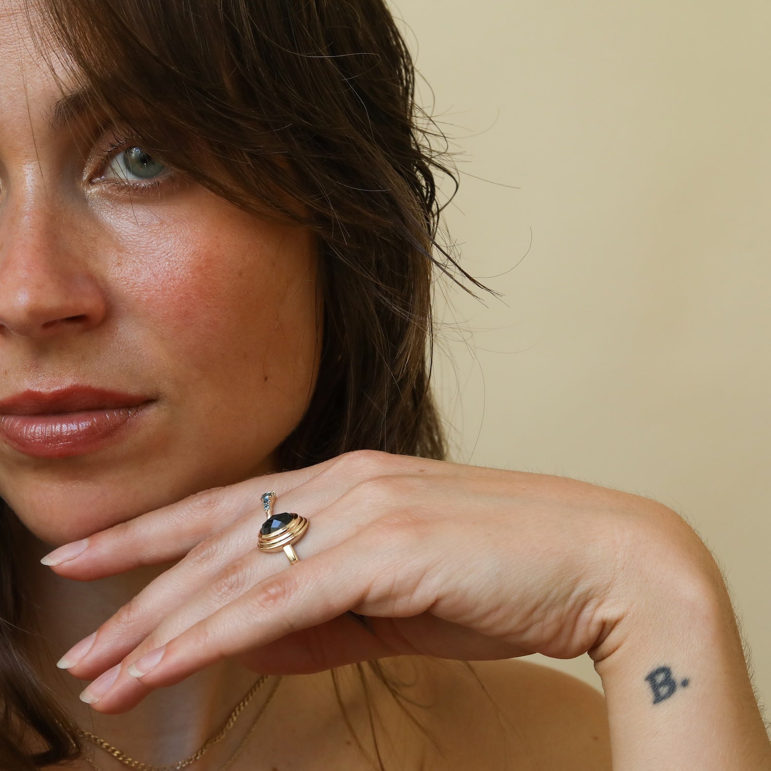 Model draagt de Florence London Blue Topaz Ring van 9 karaat goud met een ovale London Blue Topaz in een bezelzetting.