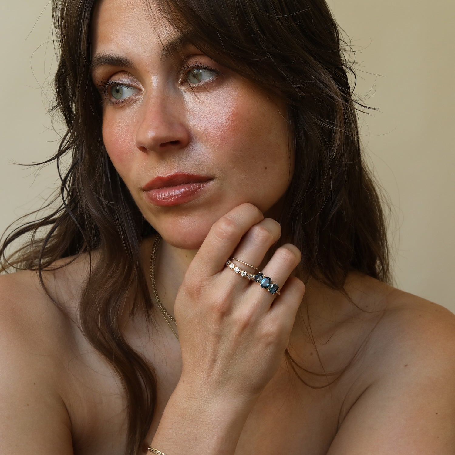 Model draagt de Isla Trio London Blue Topaz Ring van 9 karaat goud met drie London Blue Topaz edelstenen.