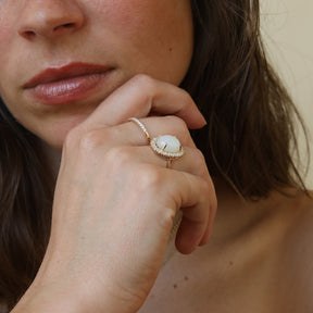 Close-up van de Livia Moonstone Halo Ring van 9 karaat goud met een grote maansteen en een halo van kleinere maanstenen.
