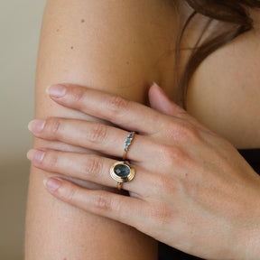 Model draagt de Lola London Blue Topaz Ring van 9 karaat goud met een rij kleine London Blue Topaz edelstenen.