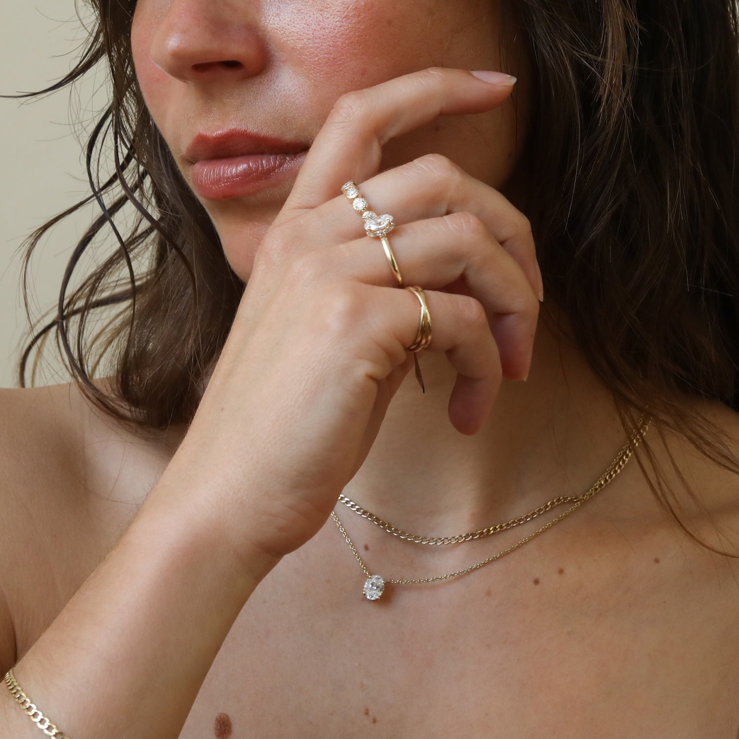 Model draagt de Olivia Diamond Half Eternity Ring van 9 karaat goud met zes lab grown diamanten in een bezel setting, gecombineerd met een ovale diamanten ring en ketting.
