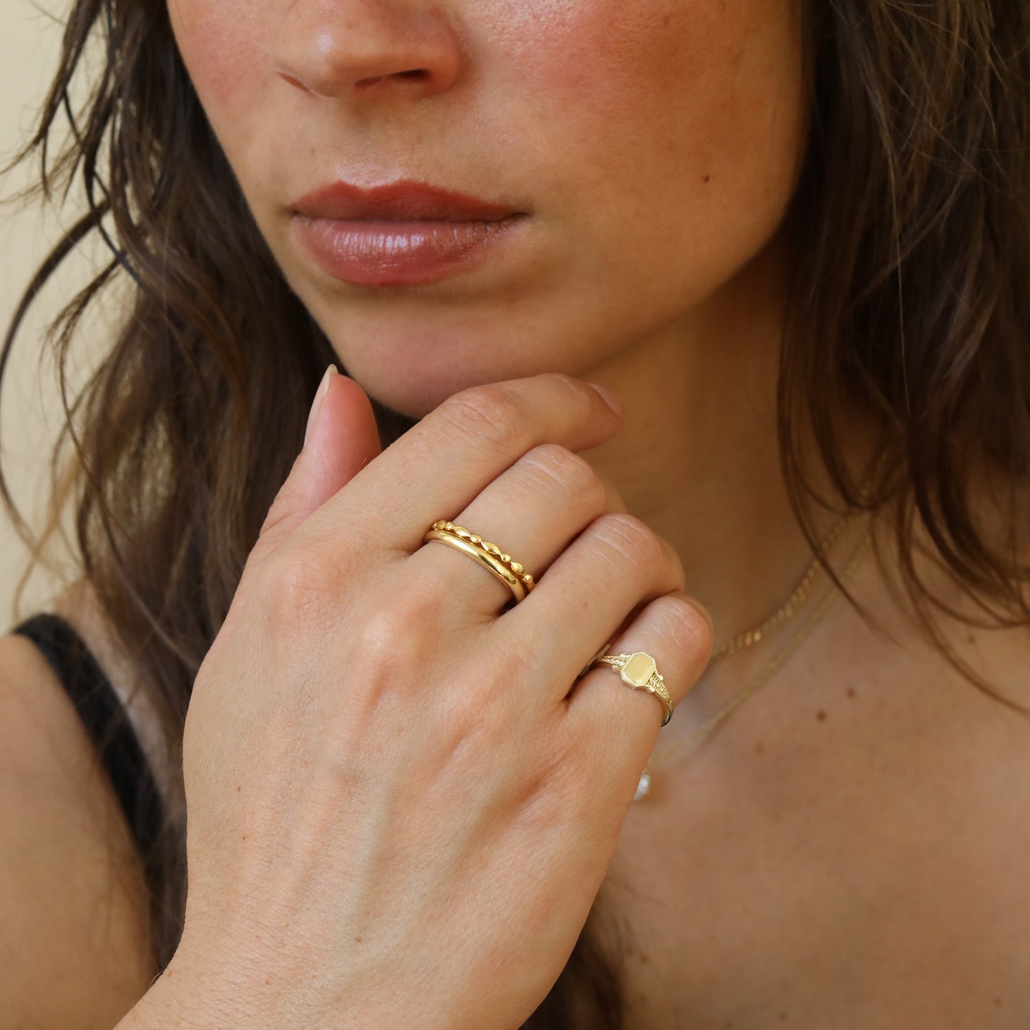 Model draagt de Tiara Octagon Signet Ring van gold plated brass met een achthoekige signetvorm.